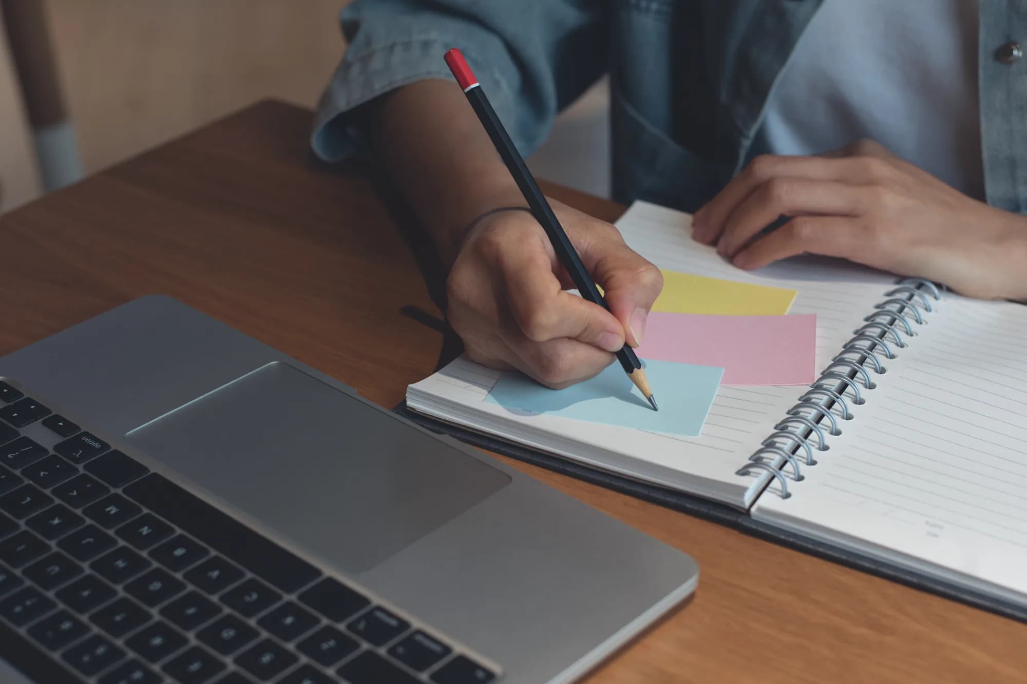 Planning keyword research by hand beside a laptop