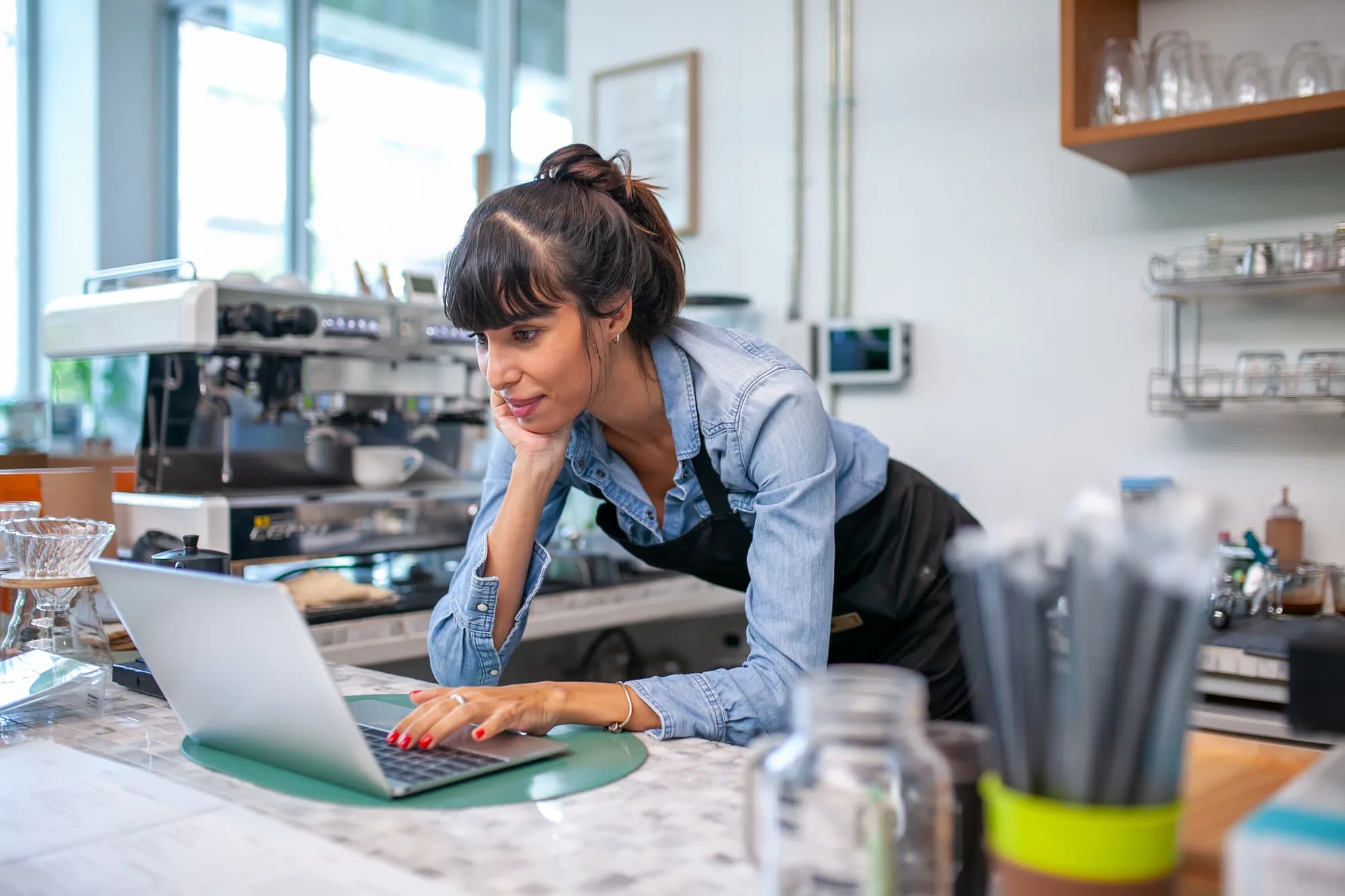 A cafe owner working at a laptop behind the counter