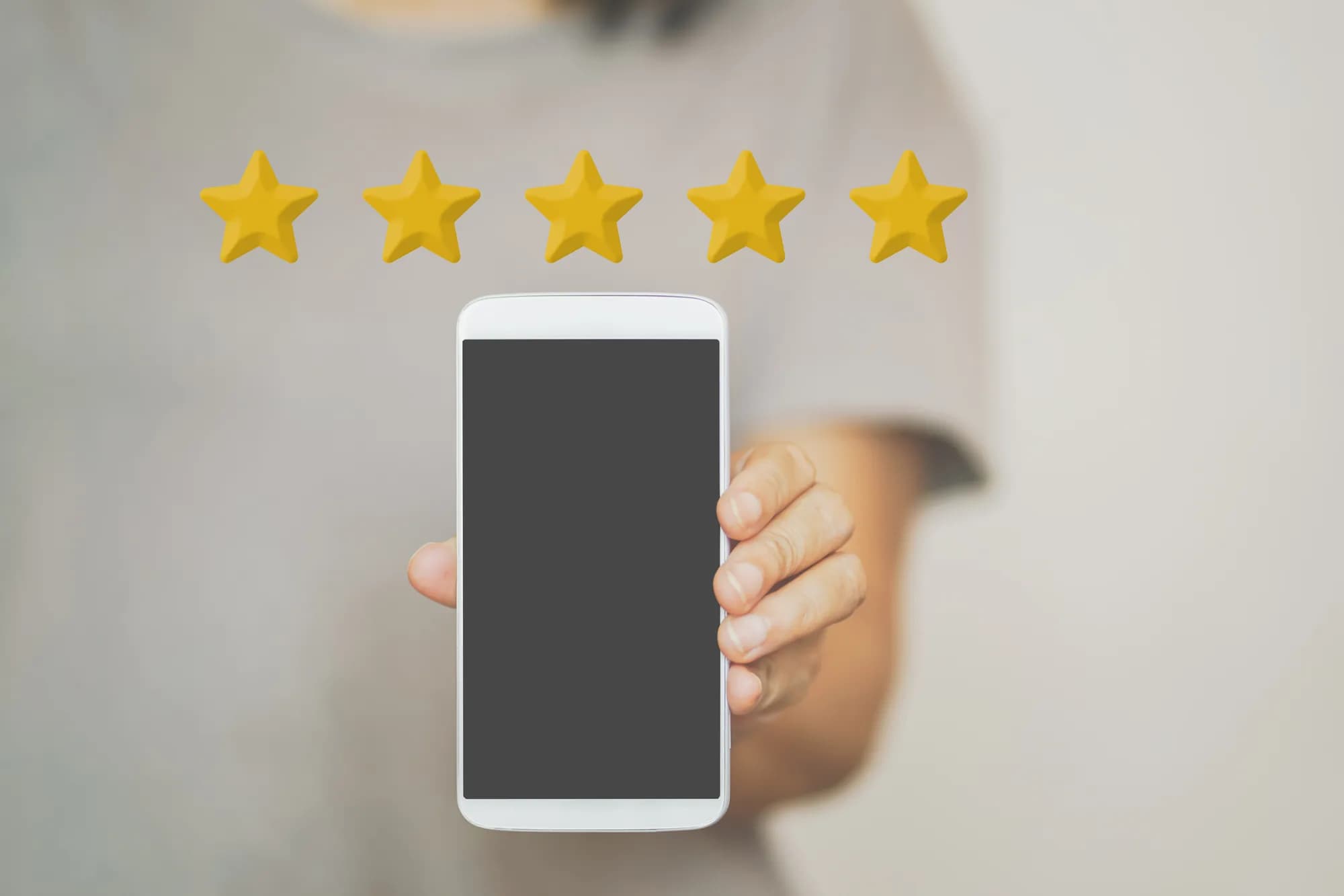 A person holding out a smartphone with five gold review stars above it
