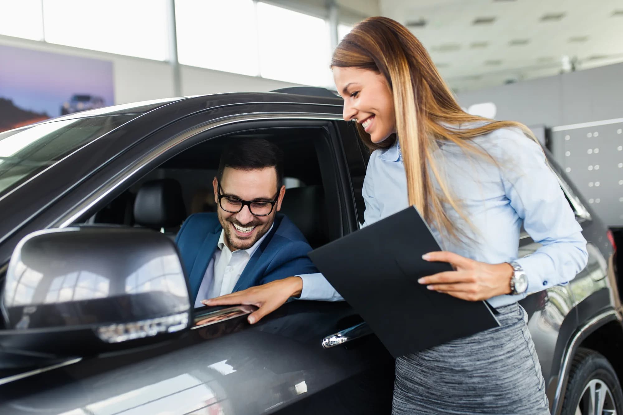 A salesperson helping a customer at a car dealership