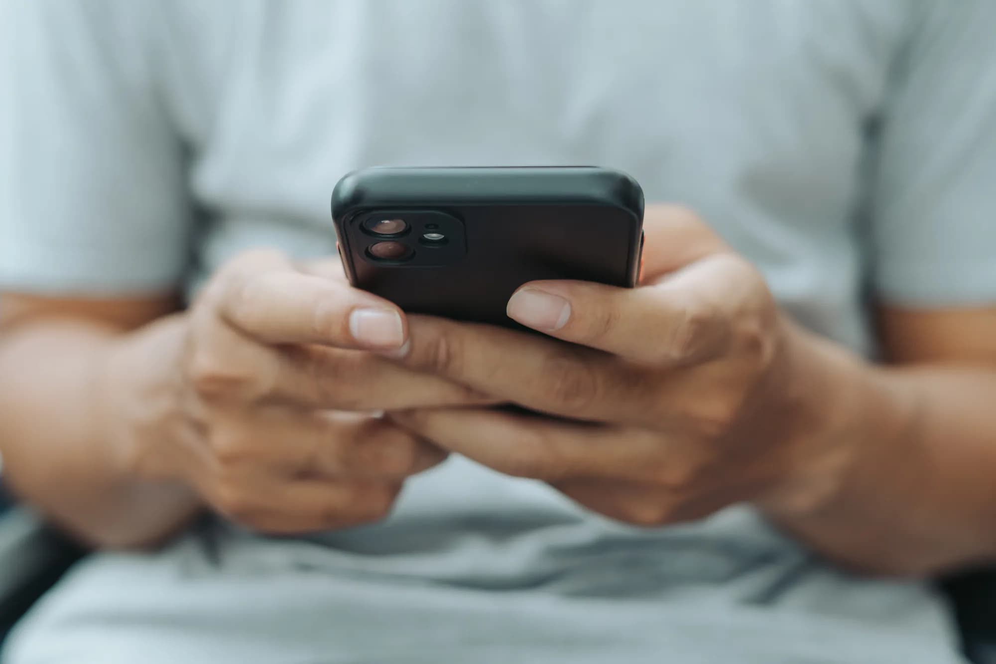 A person scrolling on a smartphone held in both hands