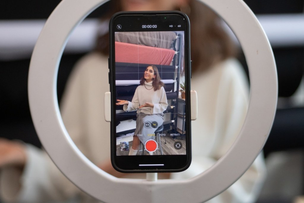 Closeup image of an influencer recording a video on a mobile phone with ring light